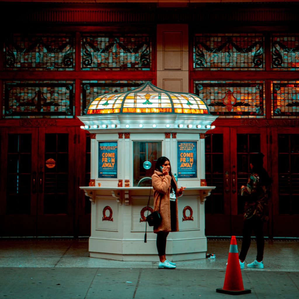 woman on the phone standing in front of a ticket booth 3042055