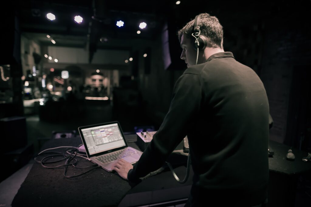 rear view man using laptop while standing nightclub min - Prism.fm